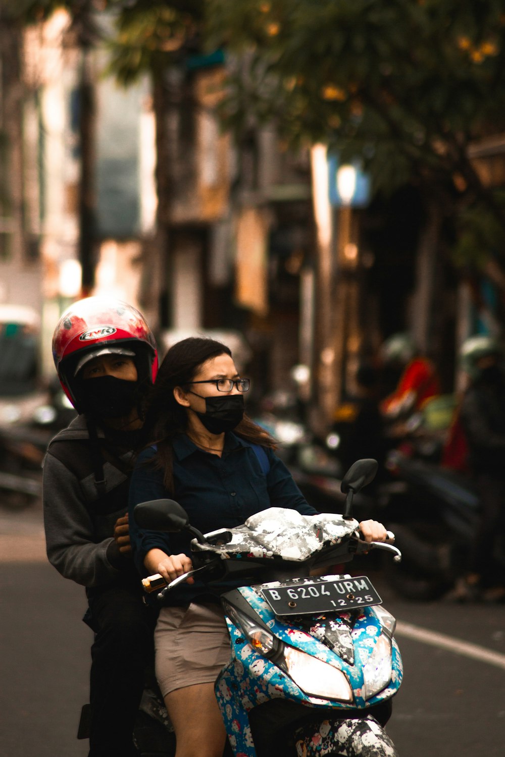 a man and a woman riding a scooter down a street
