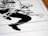 A stylized, high-contrast black and white drawing of a crouching figure with exaggerated features. The illustration appears to be from a comic book, depicting dynamic motion through bold lines and angular shapes. The figure's hand and boot are prominently detailed, capturing a sense of action.