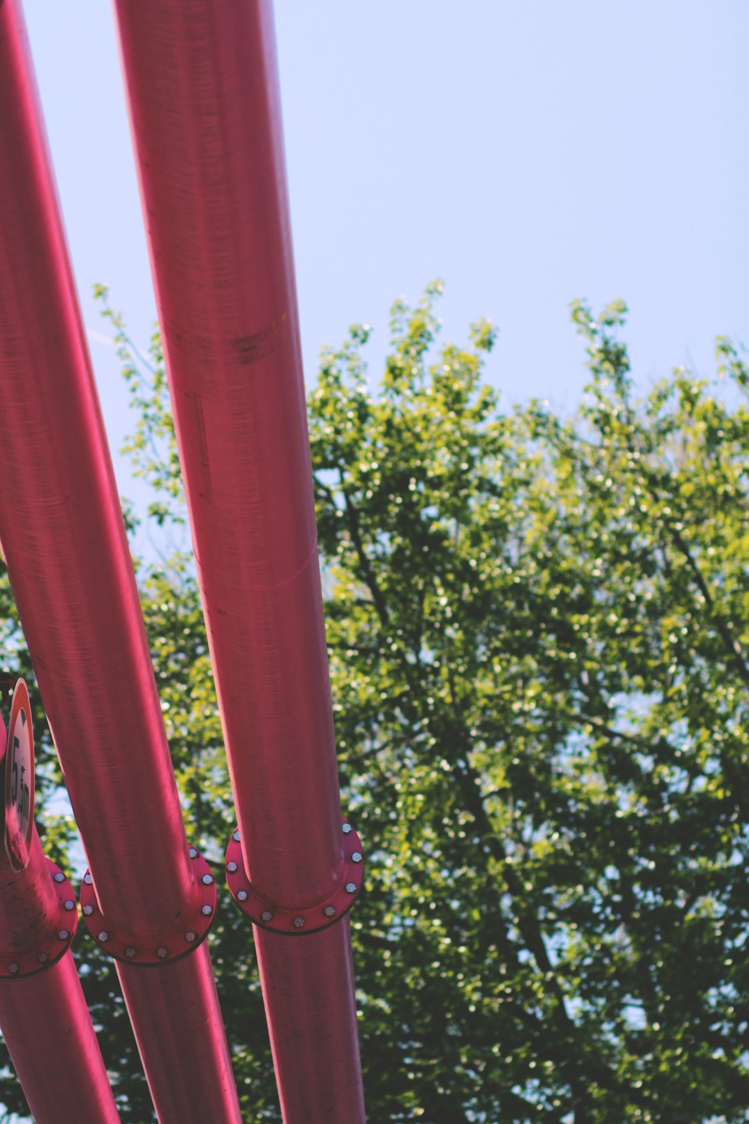 red metal pipe near green trees during daytime