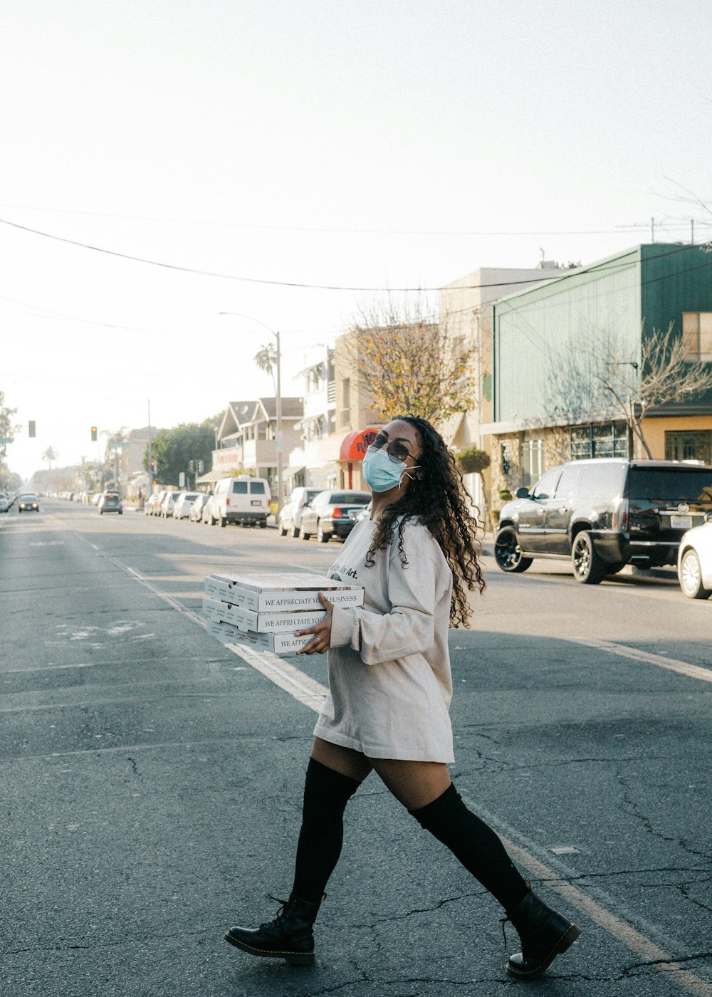 Femme en manteau blanc debout sur la route pendant la journée