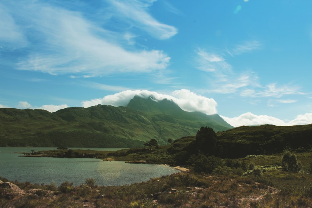 green mountains near body of water under blue sky during daytime