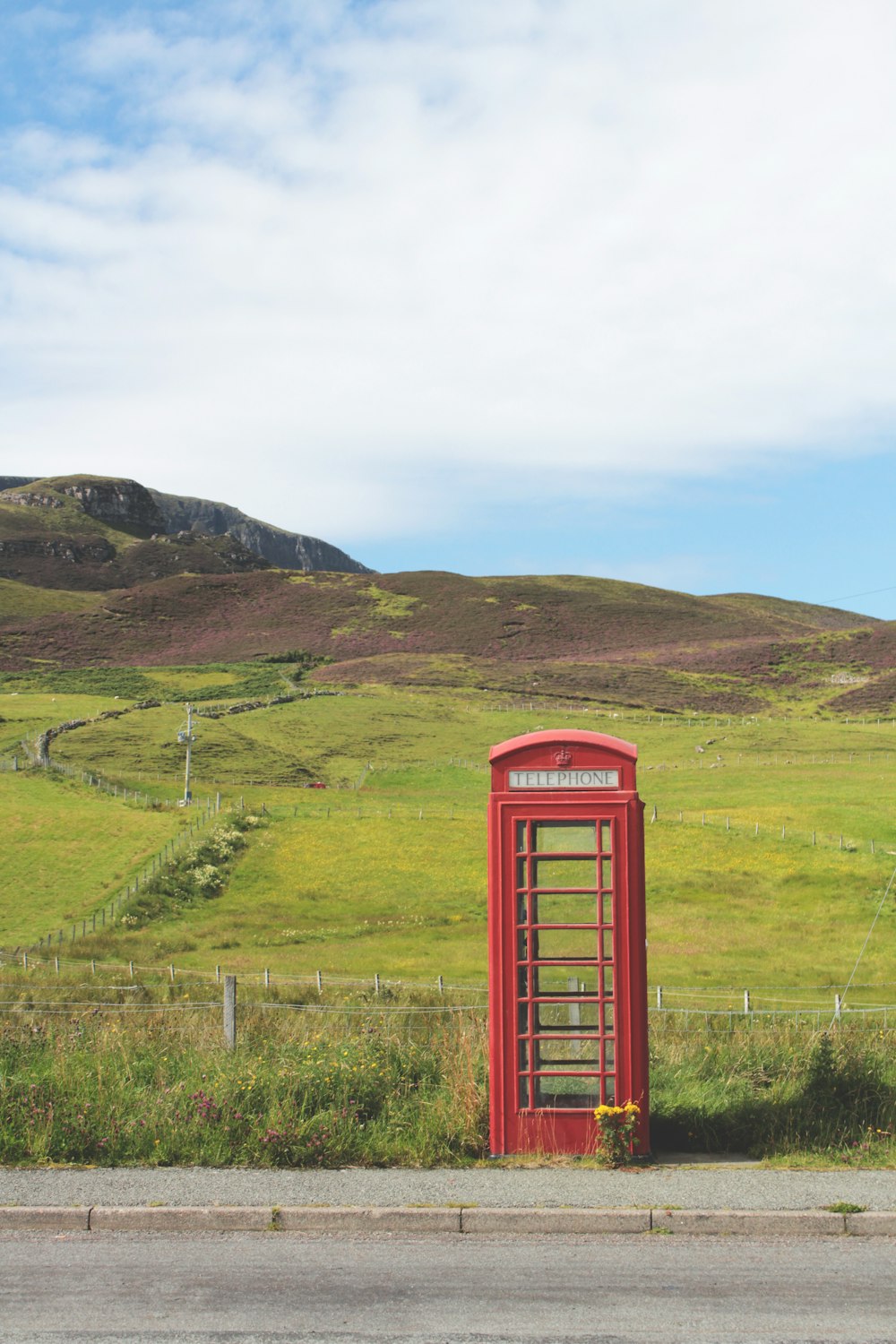 cabine téléphonique rouge sur un terrain d’herbe verte pendant la journée