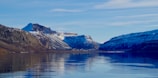 A picturesque view of the snow-capped peaks reflecting on the calm waters of a lake.