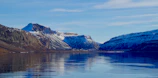 A scenic view of Torres del Paine’s iconic peaks reflected in a crystal-clear lake under a bright blue sky
