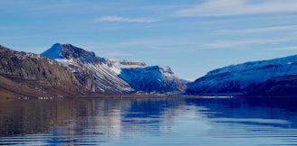 A scenic view of a serene Swiss lake surrounded by snow-capped mountains under a clear blue sky.
