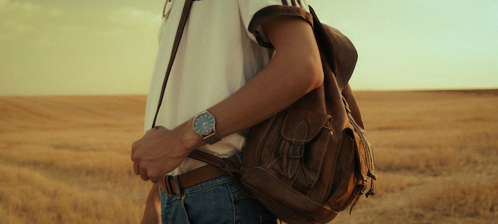 person in blue denim jeans and brown leather shoulder bag