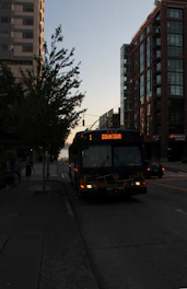 A comfortable coach bus traveling along a city street during rush hour.