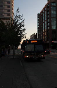 A comfortable coach bus traveling along a city street during rush hour.