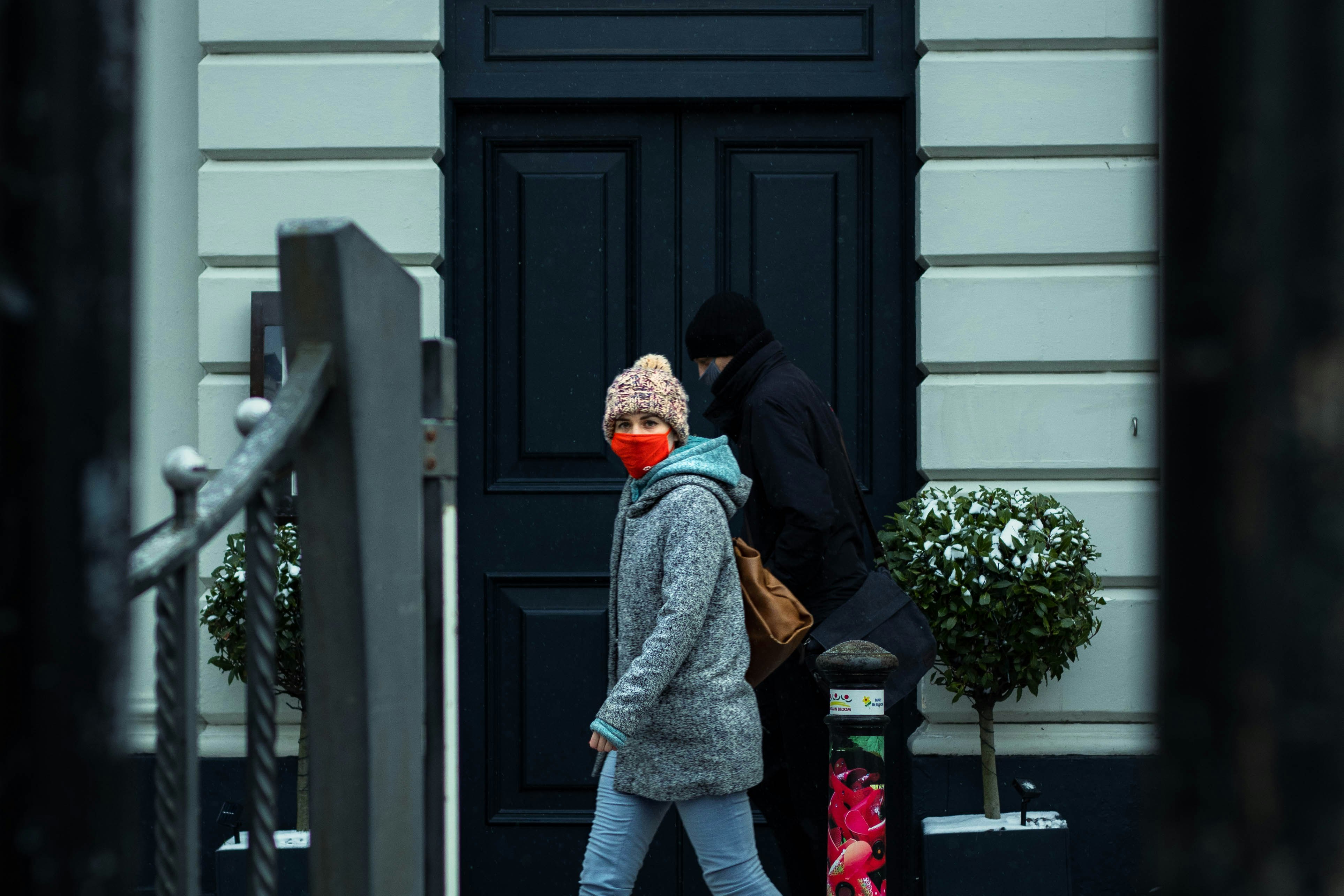 woman in gray coat standing in front of black wooden door