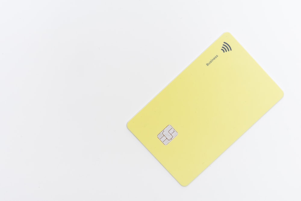 Tarjeta cuadrada amarilla sobre superficie blanca