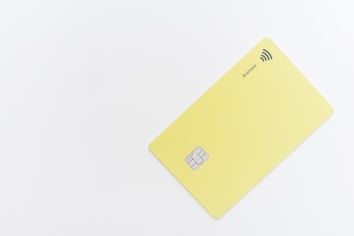 A minimalistic yellow card with a chip and contactless payment symbol is positioned against a white background. The word 'Business' is printed near the contactless symbol.