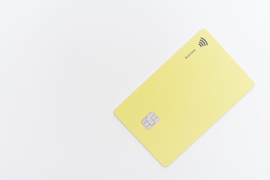 A minimalistic yellow card with a chip and contactless payment symbol is positioned against a white background. The word 'Business' is printed near the contactless symbol.