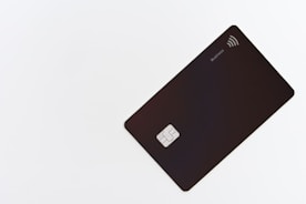 A sleek black card is placed on a white surface, featuring a chip and contactless symbol. The card is oriented diagonally and has a minimalist design with the label 'Business' on the upper right corner.