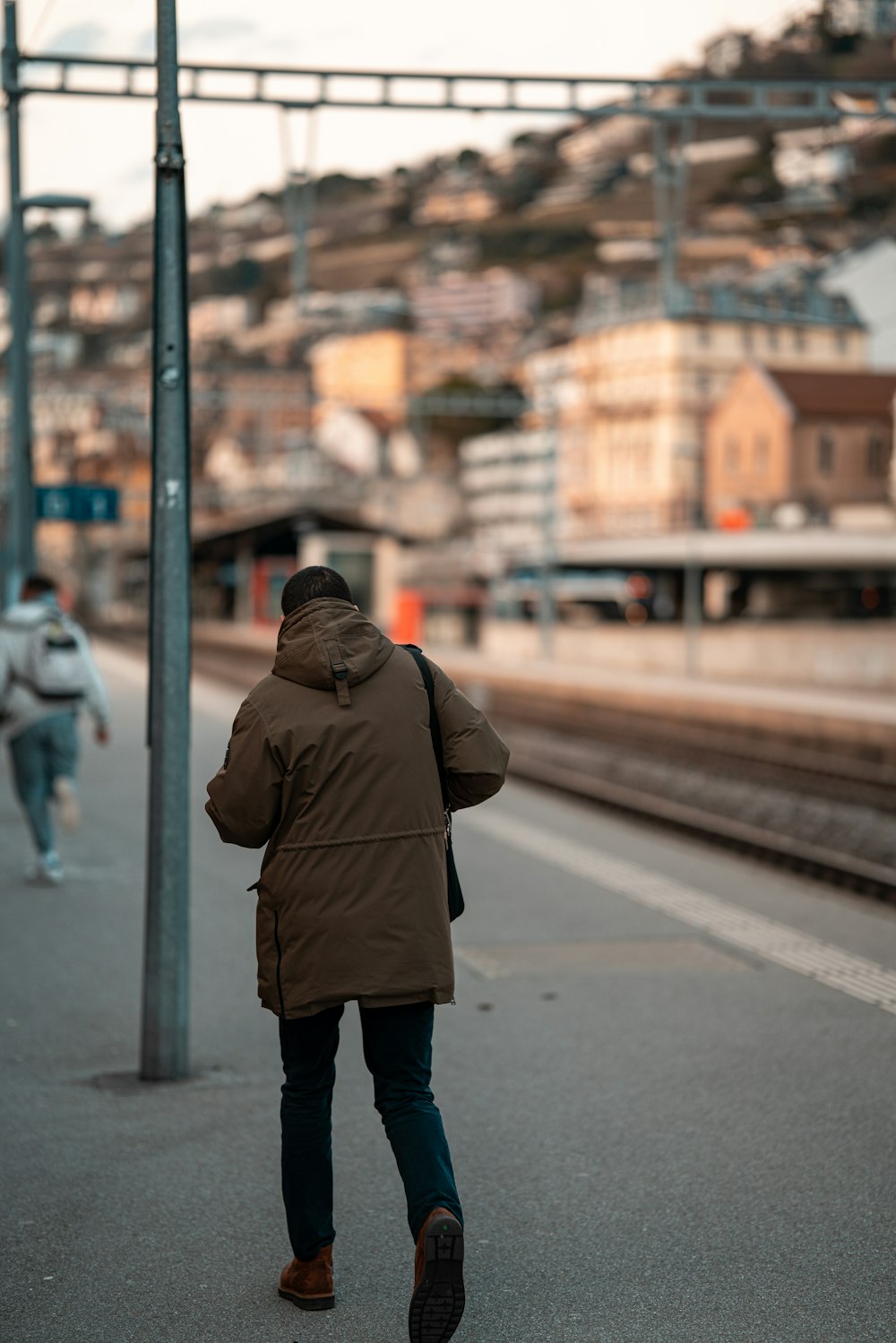 man in brown jacket standing on sidewalk during daytime