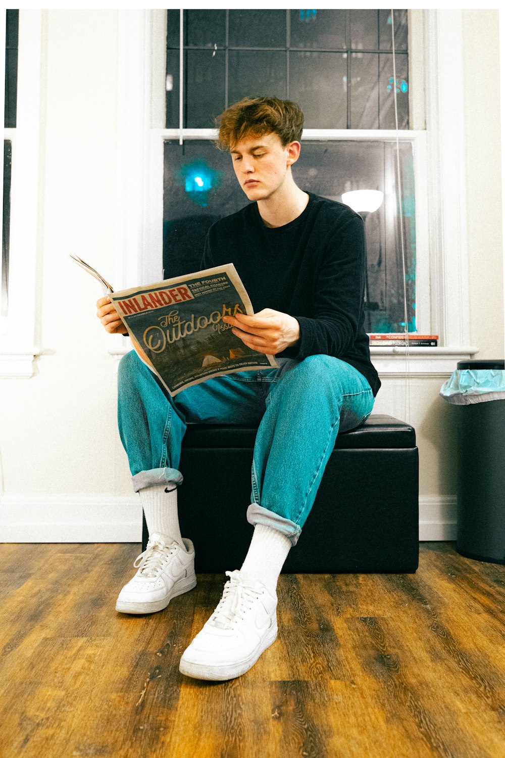 woman in black long sleeve shirt and blue denim jeans sitting on black wooden table reading