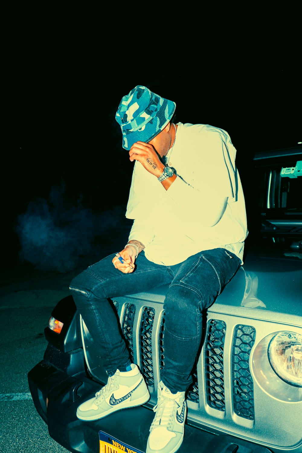 man in white hoodie and blue denim jeans sitting on white car