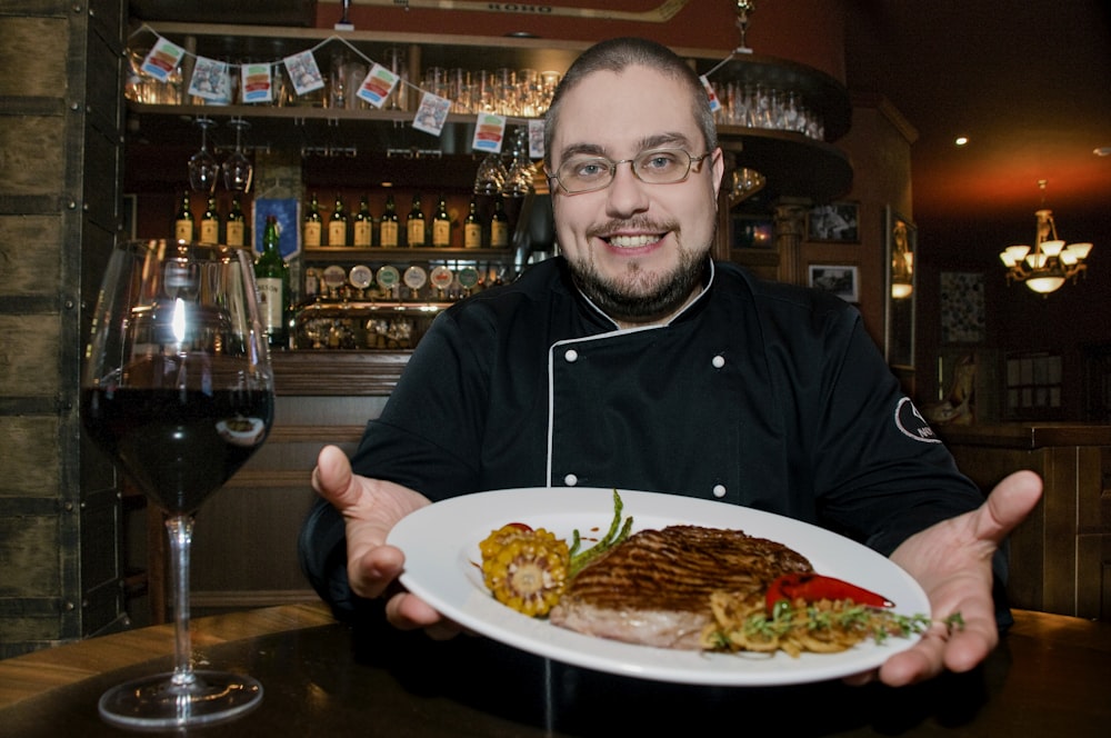 man in black zip up jacket sitting beside table with food