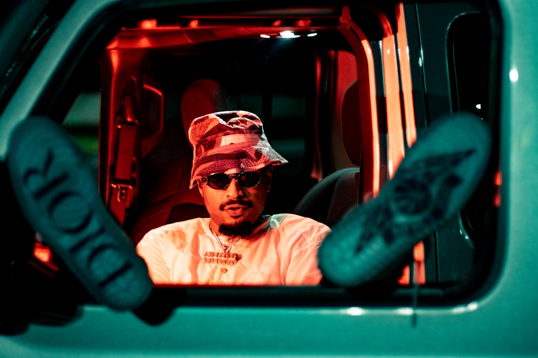 man in white shirt and black cap sitting on red car seat