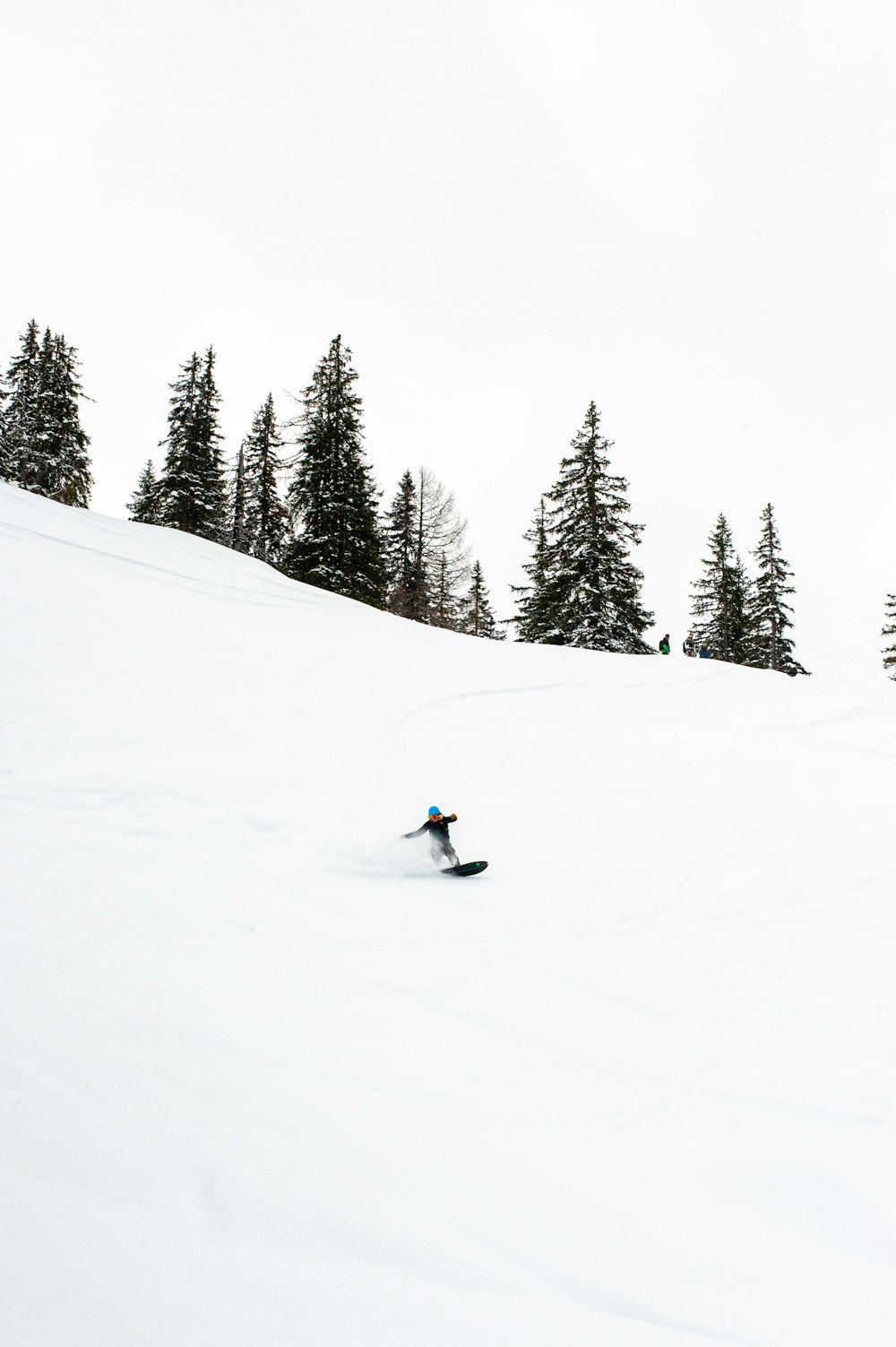 person riding on snow board on snow covered mountain during daytime