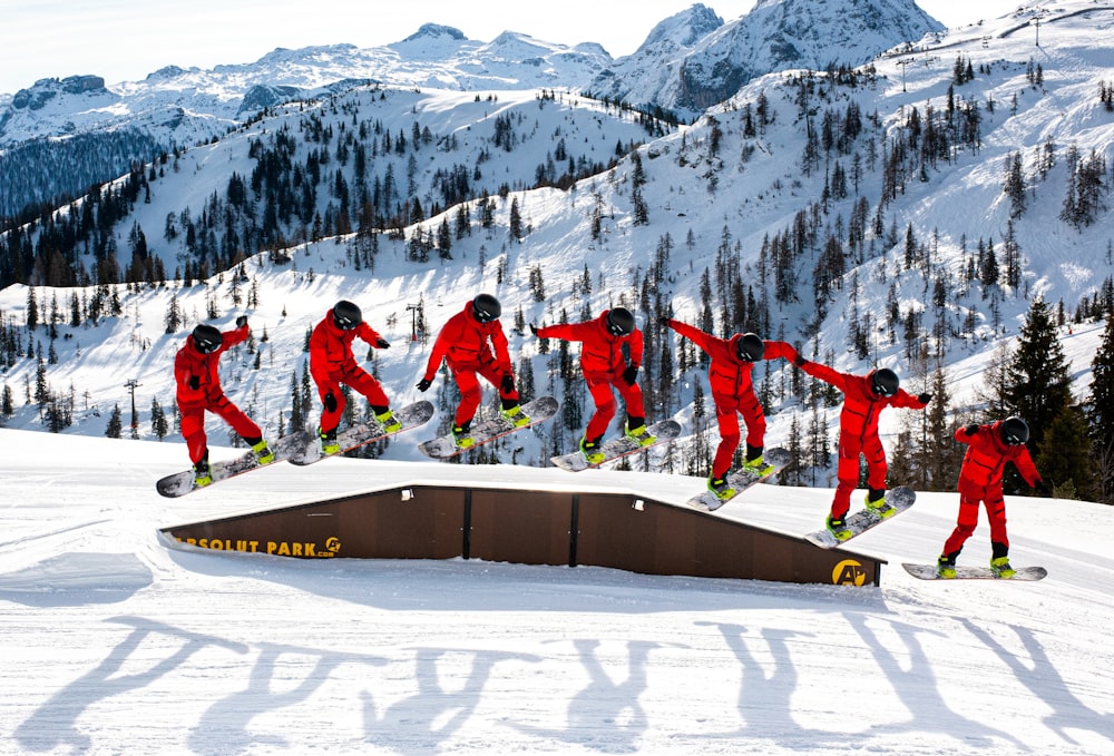 Grupo de personas con chaqueta y pantalones rojos de pie en el suelo cubierto de nieve durante el día