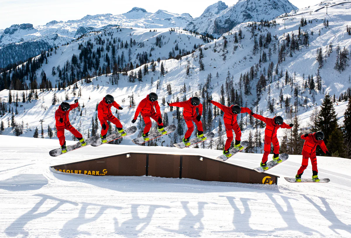 A snowboarder in red rides a terrain park box, shown as a sequence across the frame