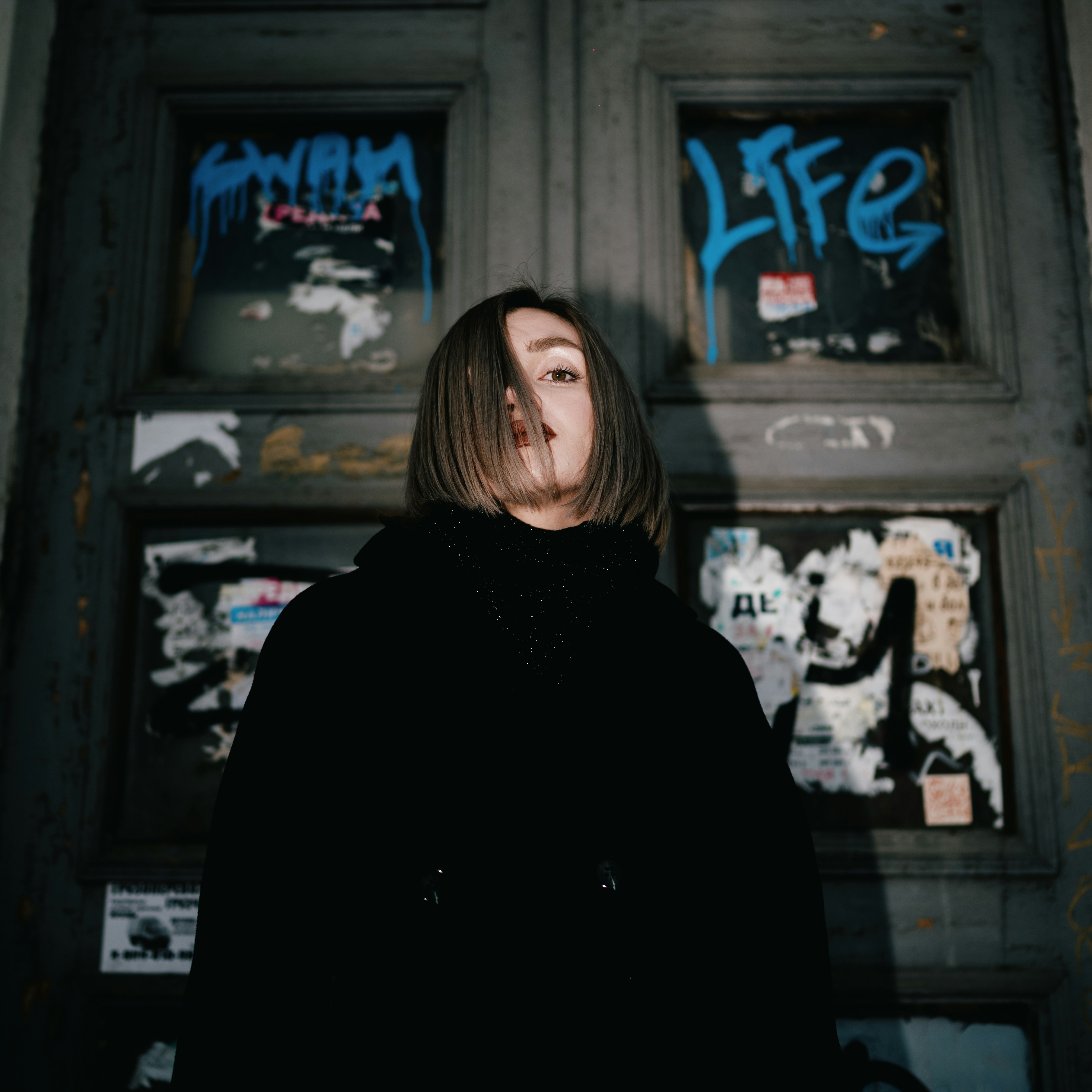 woman in black coat standing in front of black wooden framed glass window