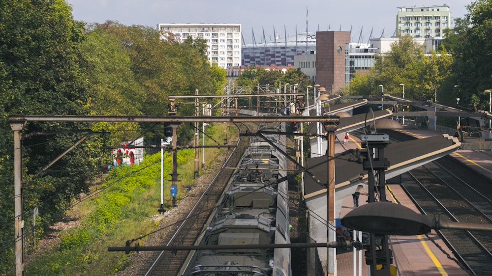 gray metal train rail near green trees and high rise buildings during daytime