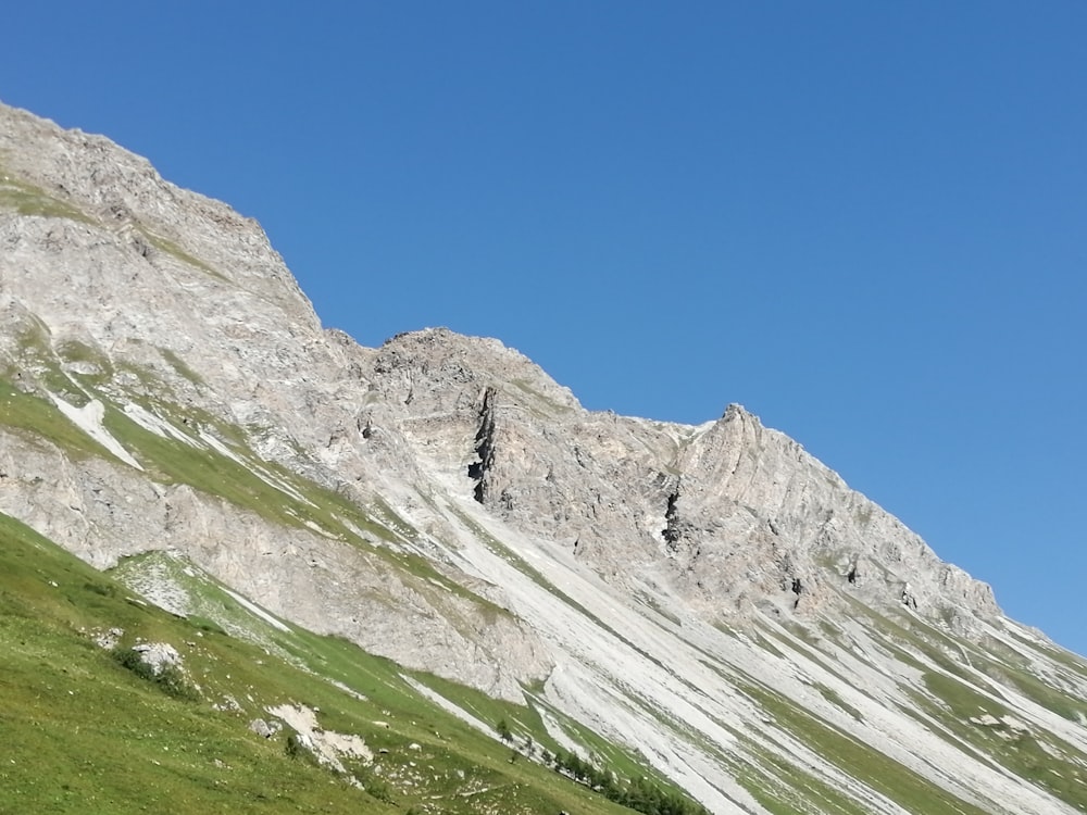 green grass field and gray mountain under blue sky during daytime