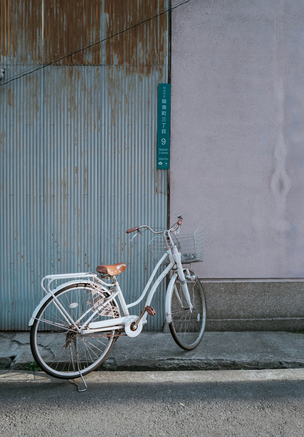 bicicleta da cidade branca estacionada ao lado da parede cinza