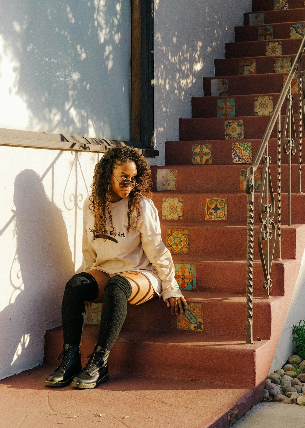 woman in white long sleeve shirt and black pants sitting on brown concrete staircase
