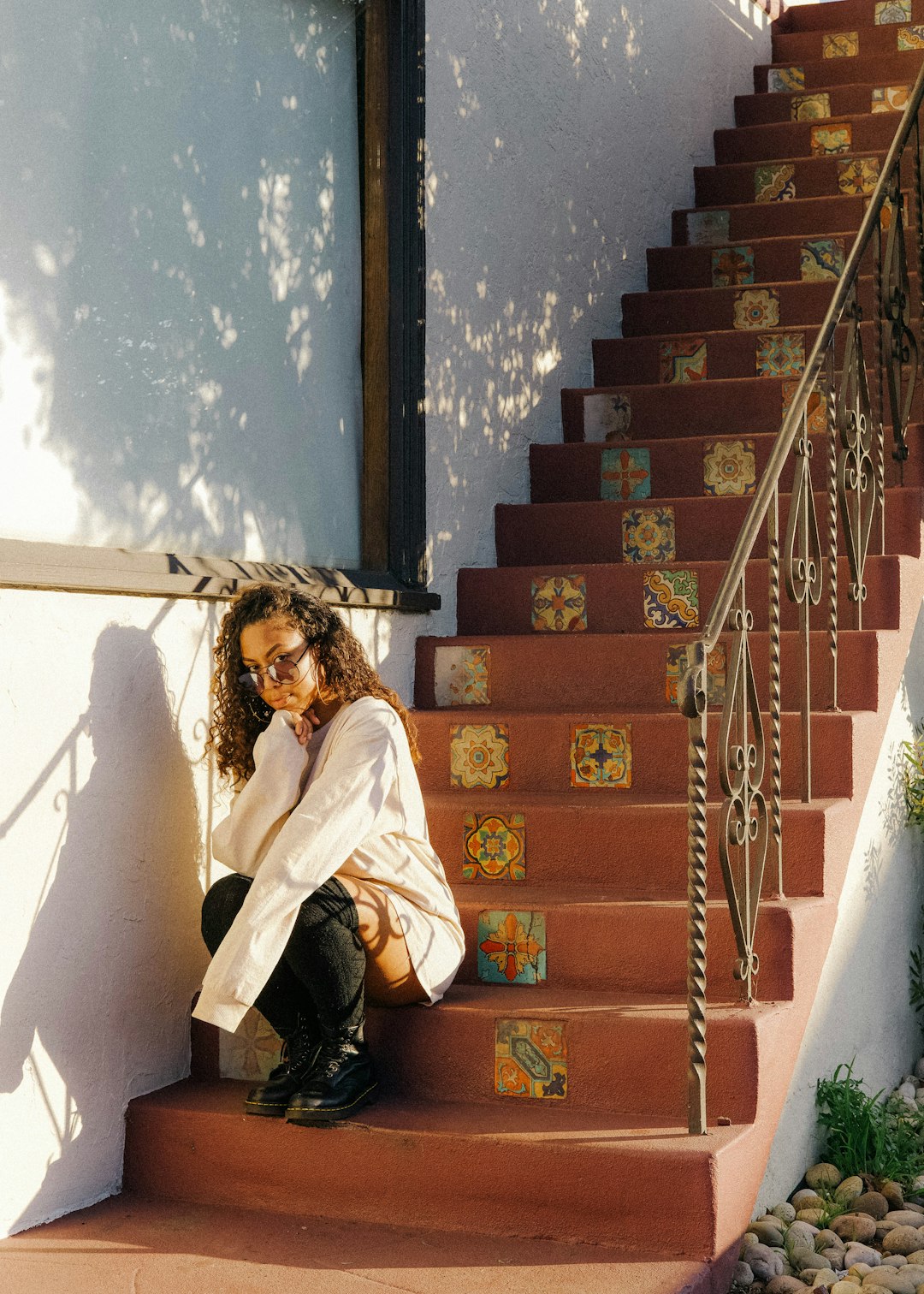 woman in white coat sitting on brown concrete staircase