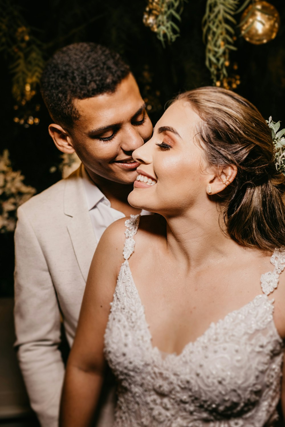woman in white floral lace wedding dress smiling beside man in gray suit