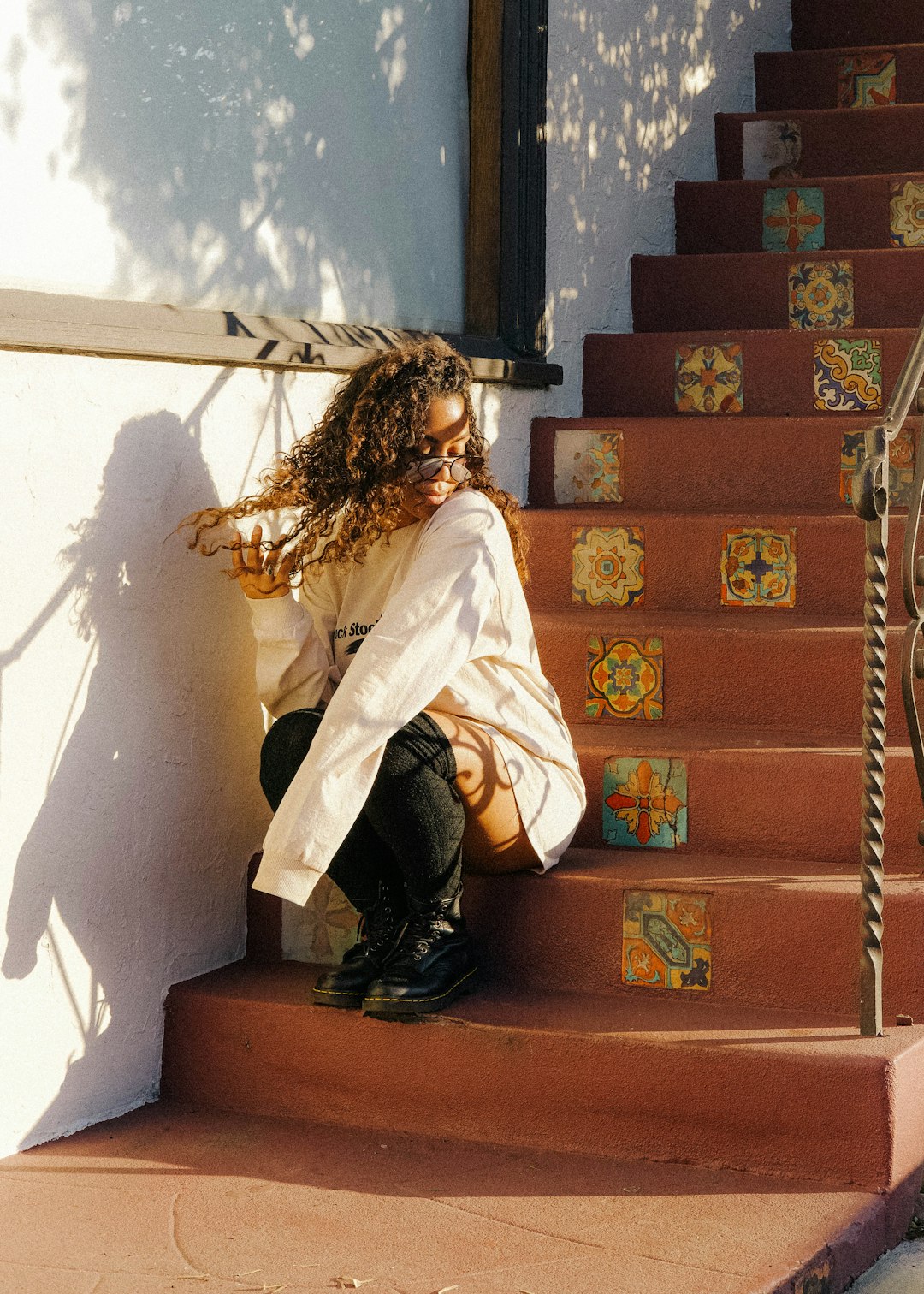 woman in white long sleeve shirt and black pants sitting on brown concrete stairs