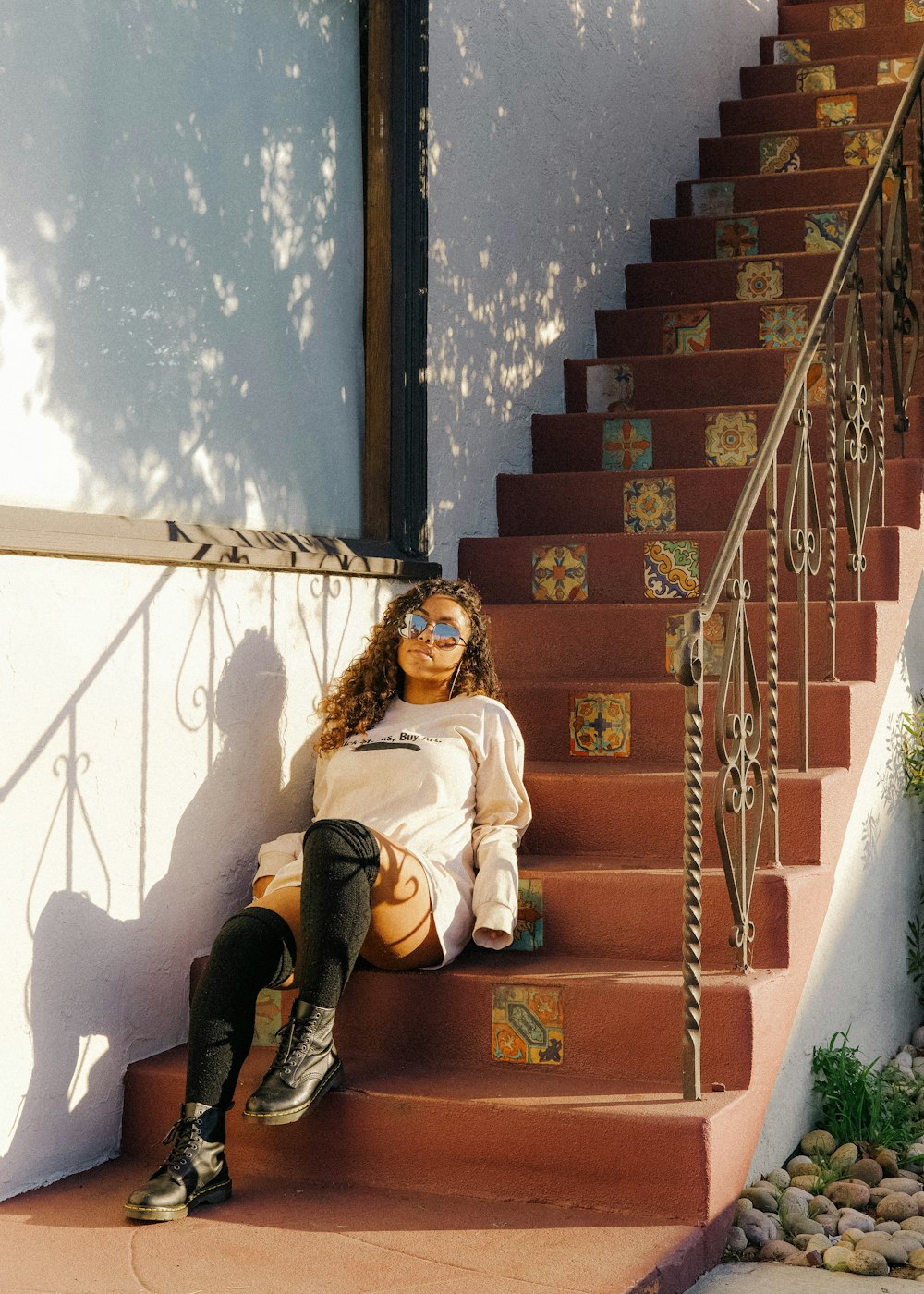 Femme en chemise blanche à manches longues et jean en jean noir assise sur un escalier en béton brun