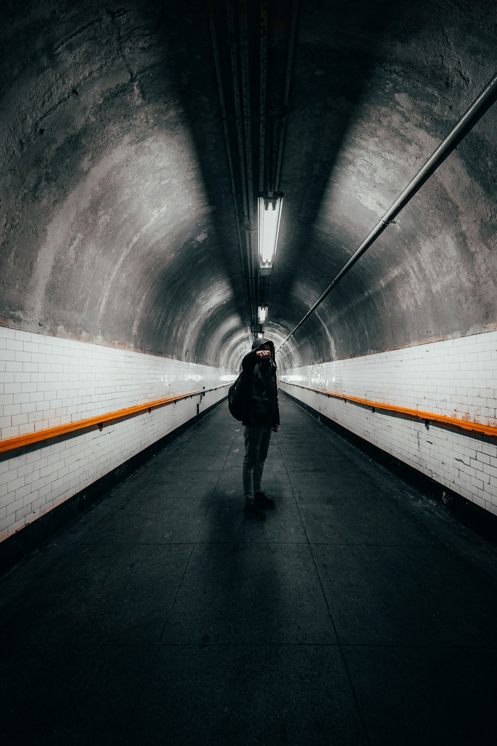man in black jacket walking on tunnel