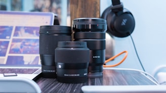 Close-up of a camera lens and creative tools arranged neatly on a white workspace with orange accents.
