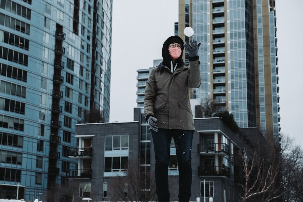 man in gray jacket standing near high rise building