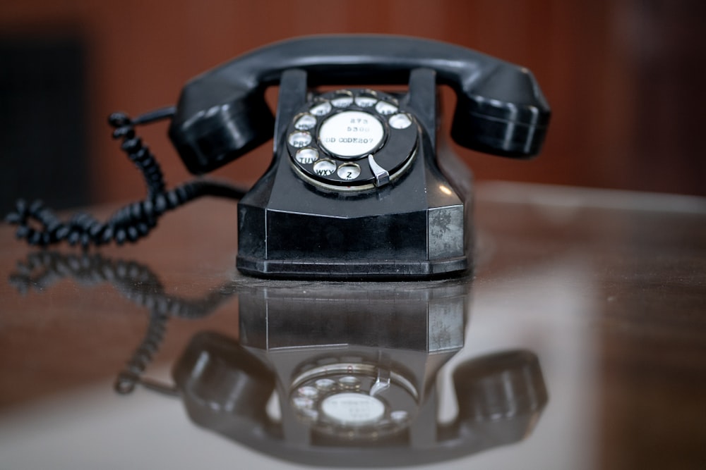 black rotary phone on brown wooden table