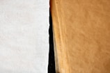 A close-up view of a stack of brown paper sheets next to a single white textured sheet, showcasing the contrast between the two surfaces.
