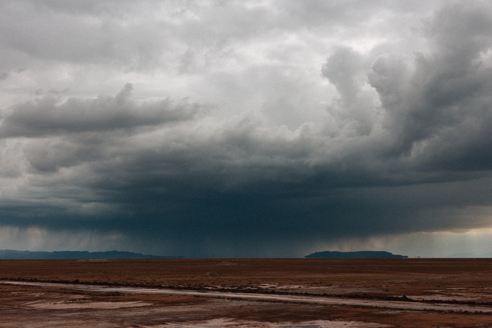 brown field under white clouds