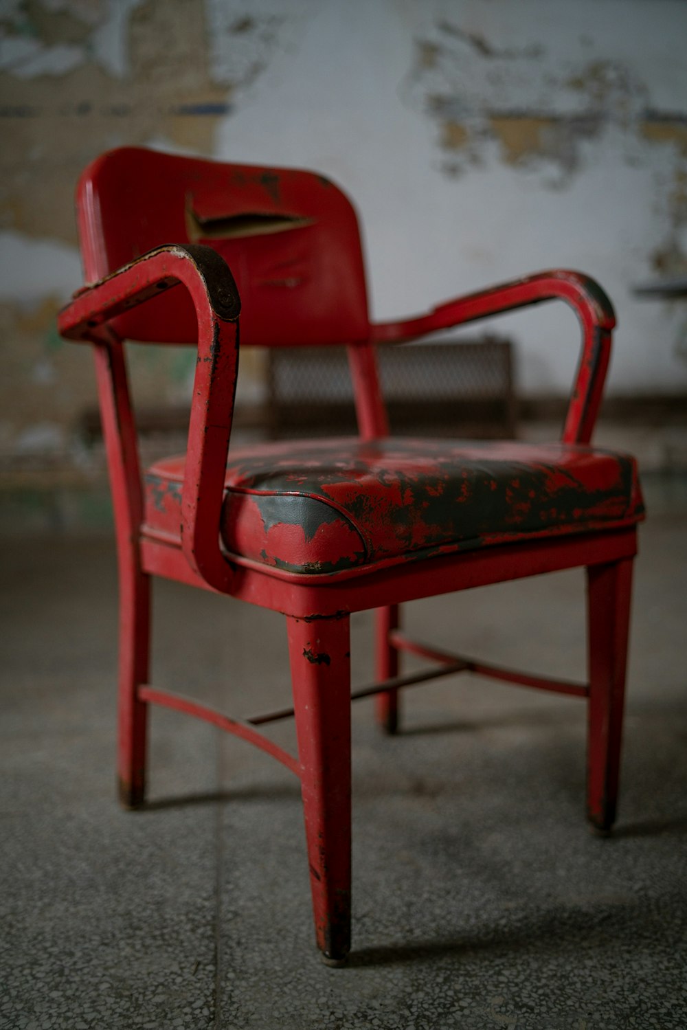 灰色のコンクリートの床に赤いプラスチック製の肘掛け椅子