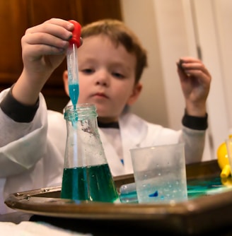 boy in white long sleeve shirt holding red and clear plastic tool