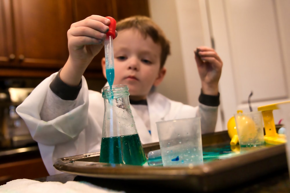 boy in white long sleeve shirt holding red and clear plastic tool