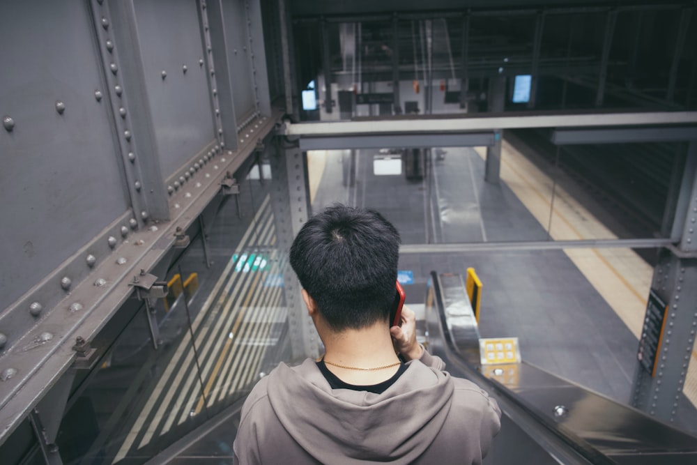 man in gray crew neck shirt standing in front of black and gray escalator