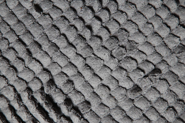 Close-up of breathable, skin-friendly fabric texture on a summer quilt laid over a mattress.