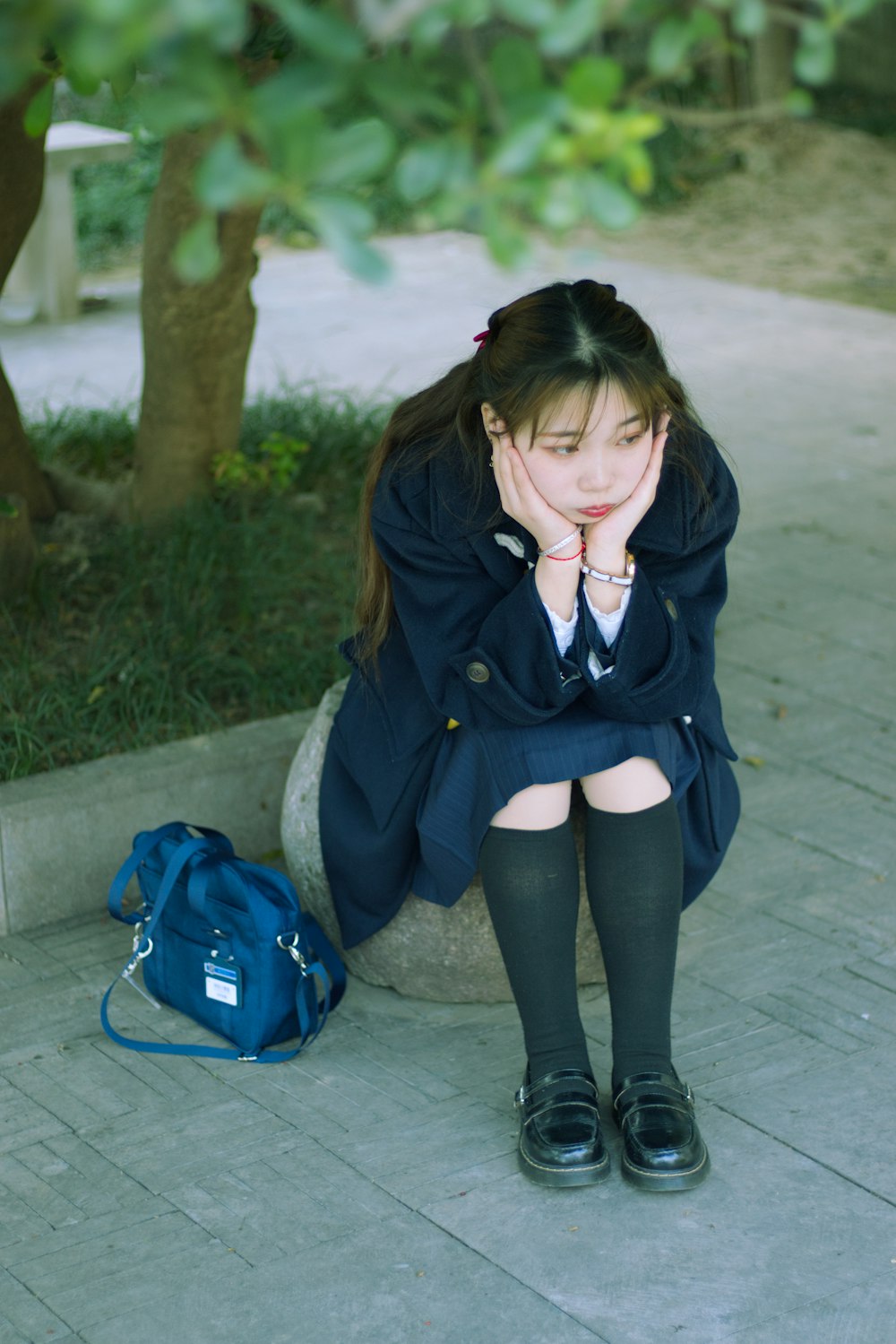 woman in black jacket and black pants sitting on concrete bench