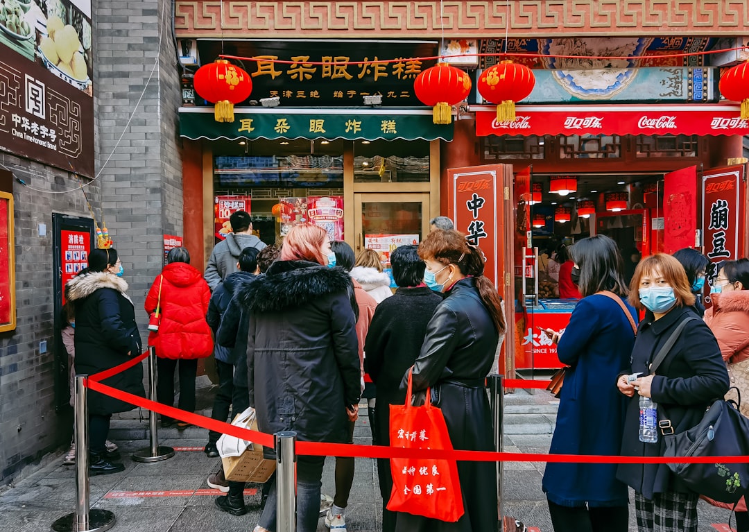 people in red and black jackets standing near red and white store during daytime