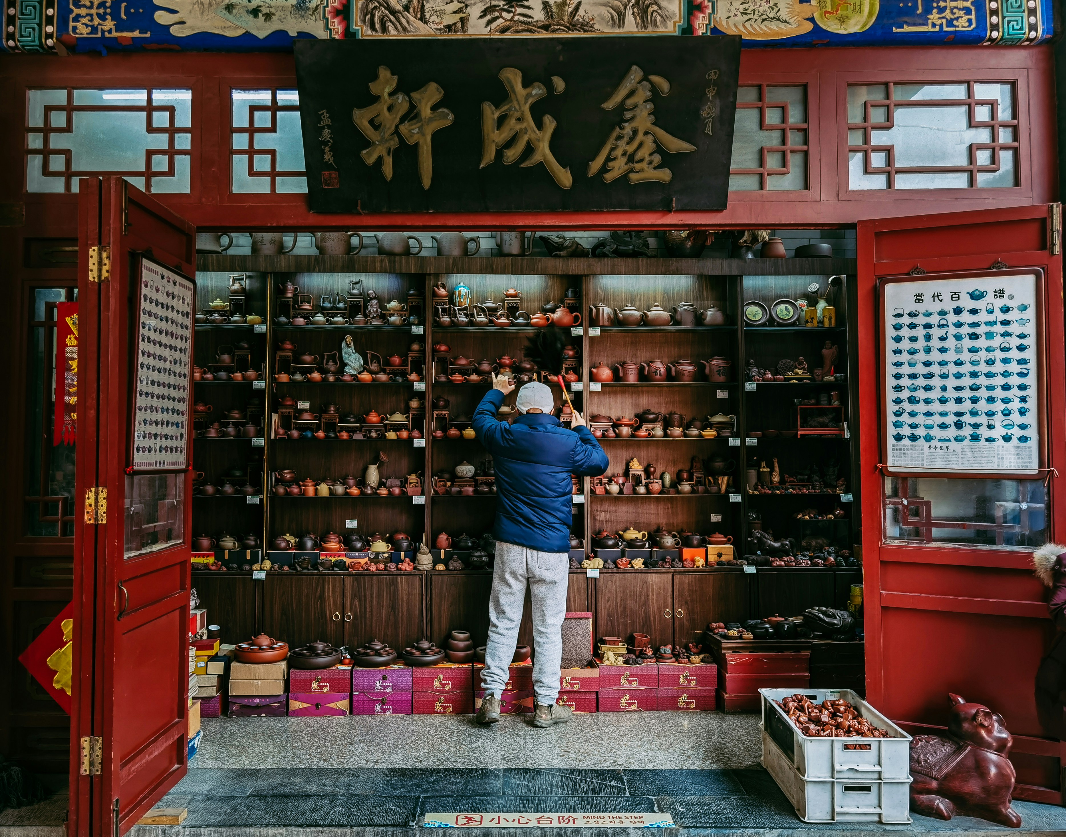man in blue polo shirt standing in front of red and black wooden shelf