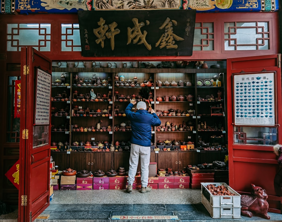 man in blue polo shirt standing in front of red and black wooden shelf