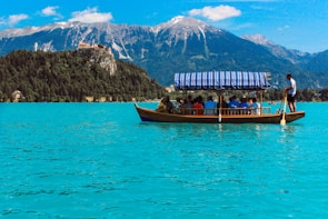 people on boat on lake near mountain during daytime
